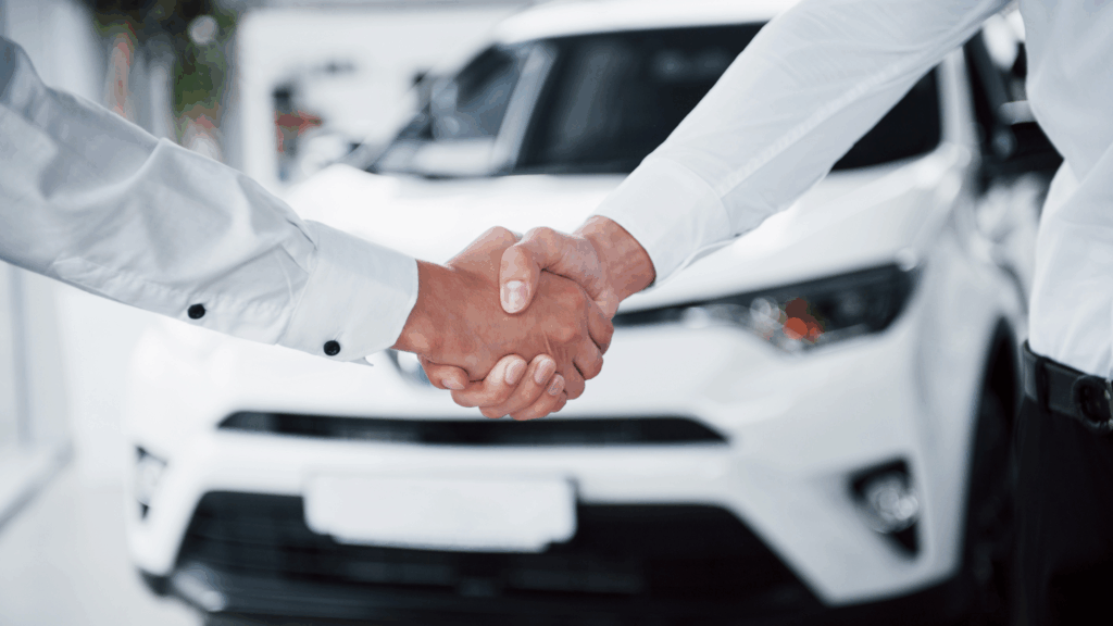 shaking hands in front of car